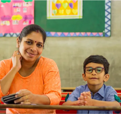 School Teacher and Student Sitting at Desk in Classroom