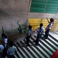 Students painting sea creature murals on a concrete stairwell wall.