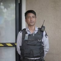 School Security Guard Standing On Duty Near Campus Entrance