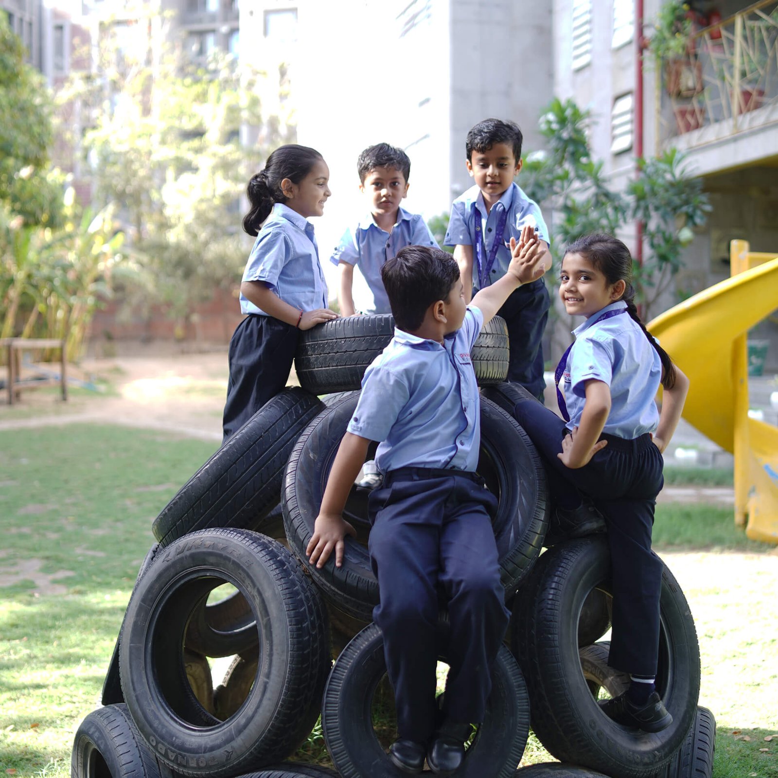 Schoolchildren High-Fiving on Playground Tire