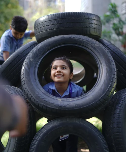 Schoolgirl Looking Through a Playground Tire